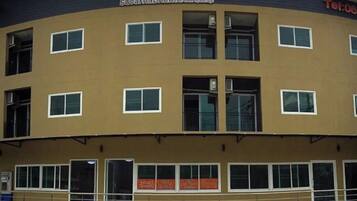 Un edificio a più piani con facciata lineare, numerose finestre e un cartello sopra l'ingresso.