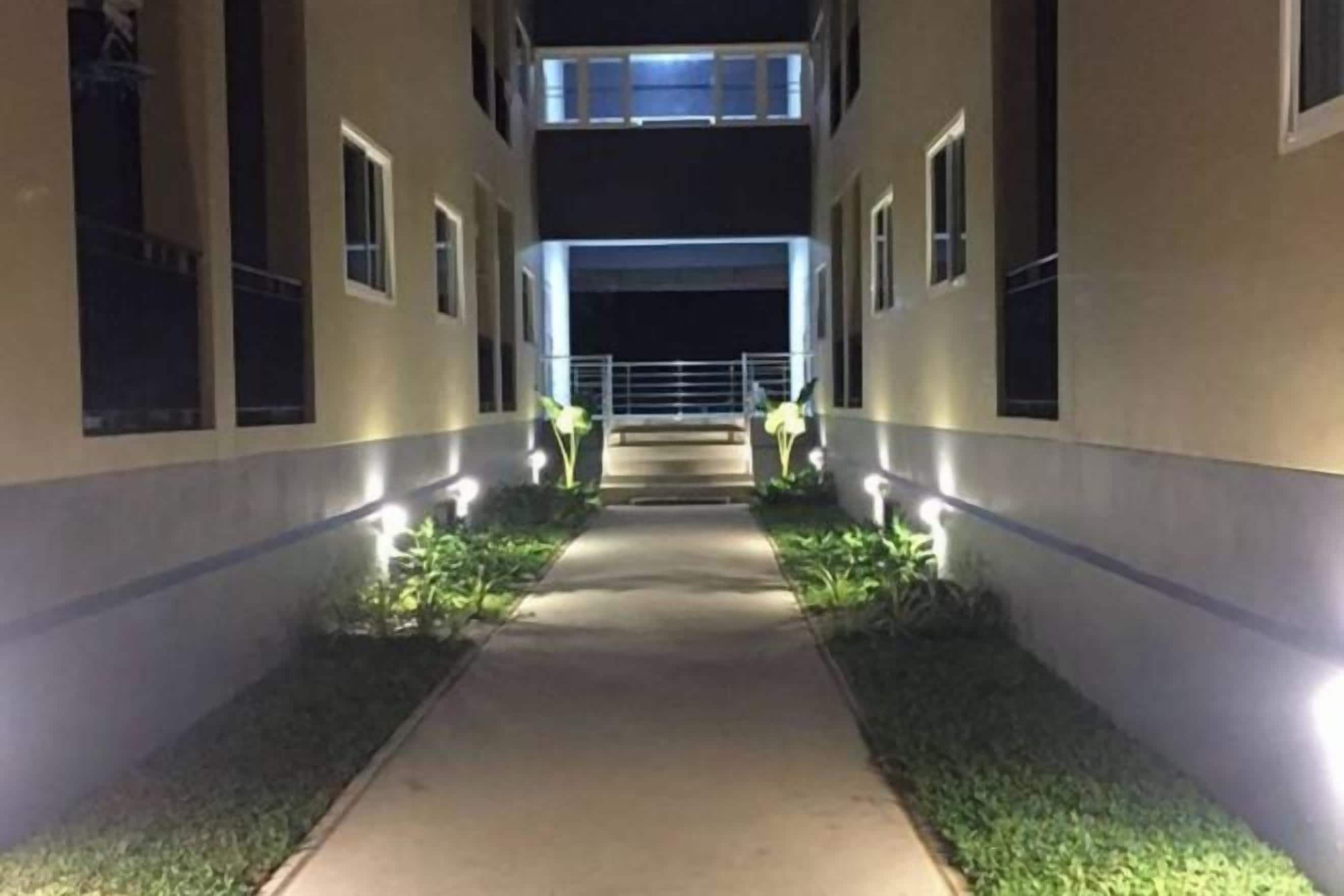 Un camí flanquejat per edificis amb finestres il·luminades i una passera central.
