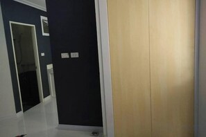 A hallway with a dark wall, a wooden door, and a white floor. - A-Place Suvarnabhumi (Bang Phli)