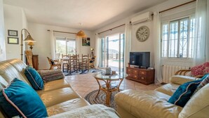 A spacious living room with a sofa set, a dining table, and a television. - Casa Hermanas Alcaucín by Ruralidays (Málaga)