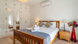 A neatly arranged bedroom with a bed, bedside tables, a wardrobe, and an air conditioning unit. - Casa Hermanas Alcaucín by Ruralidays (Málaga)