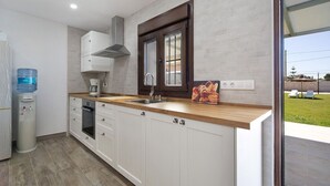 Una cocina moderna con armarios blancos, encimera de madera, horno empotrado y dispensador de agua.