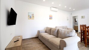 Una sala de estar moderna con un sofá color beige, una mesita de madera y un televisor montado en la pared.