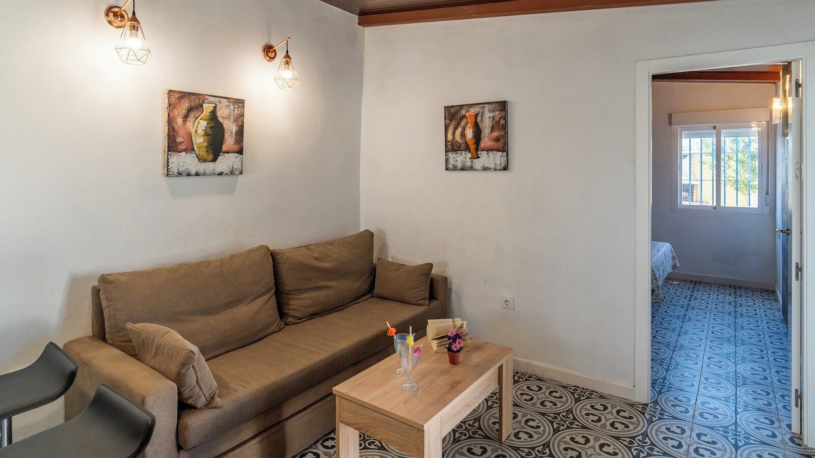A living room with a brown sofa, a wooden coffee table, and two wall-mounted light fixtures.