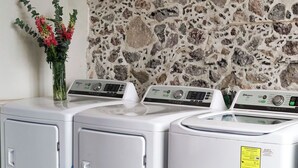 Une buanderie avec trois machines à laver blanches et un vase de fleurs posé sur le comptoir.