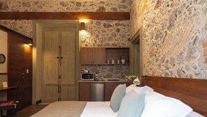 Une chambre avec un mur en pierre, une tête de lit en bois et un lit avec des oreillers.