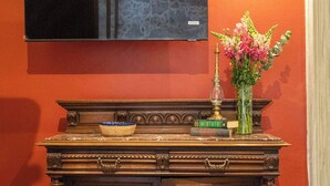 Une console en bois sur laquelle est fixée une télévision, un vase avec des fleurs et un petit coffre en dessous.