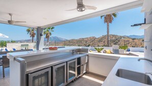 Cocina exterior moderna con vistas a un paisaje montañoso.