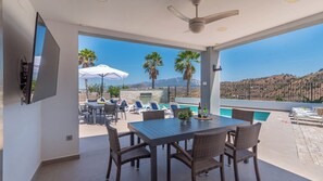 Un espace de restauration extérieur moderne, doté d’une piscine et offrant une vue sur les montagnes.