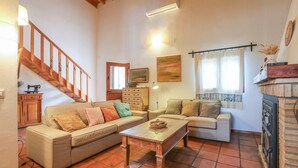 Una sala de estar acogedora con una escalera de madera, una chimenea y un televisor.