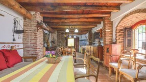 A rustic dining area with a long table, wooden chairs, and a basket of flowers. - Alojamiento Turístico Casa El Coronel Fuente Obejuna by Ruralidays (Córdoba)