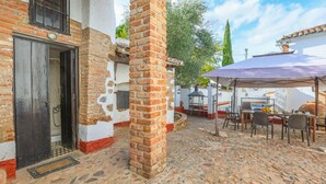 A courtyard with a stone floor, outdoor seating, and a covered area with a table and chairs. - Alojamiento Turístico Casa El Coronel Fuente Obejuna by Ruralidays (Córdoba)