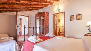 A hotel room with two beds, a wooden ceiling, a mirror, and a bathroom visible through an open door. - Alojamiento Turístico Casa El Coronel Fuente Obejuna by Ruralidays (Córdoba)