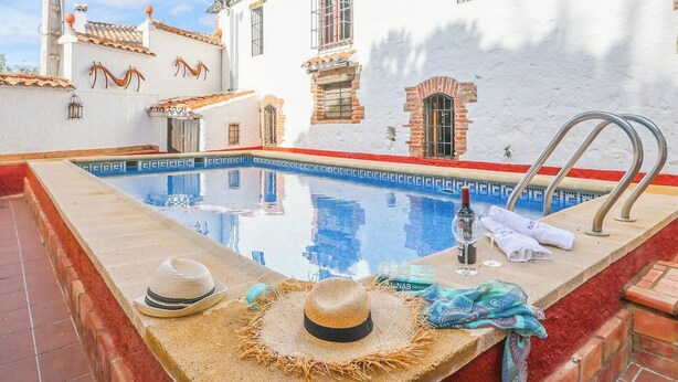A swimming pool with a red and white tiled edge, a metal ladder, and a towel rack. - Alojamiento Turístico Casa El Coronel Fuente Obejuna by Ruralidays (Córdoba)