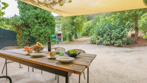 Un área de comedor al aire libre con una mesa de madera, sillas y un toldo amarillo.