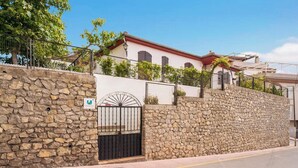 Un muro de piedra con una reja metálica y un cartel que indica zona rural.