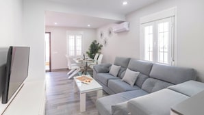Una sala de estar moderna con un sofá gris, una mesa de centro de vidrio y un televisor de pantalla plana.