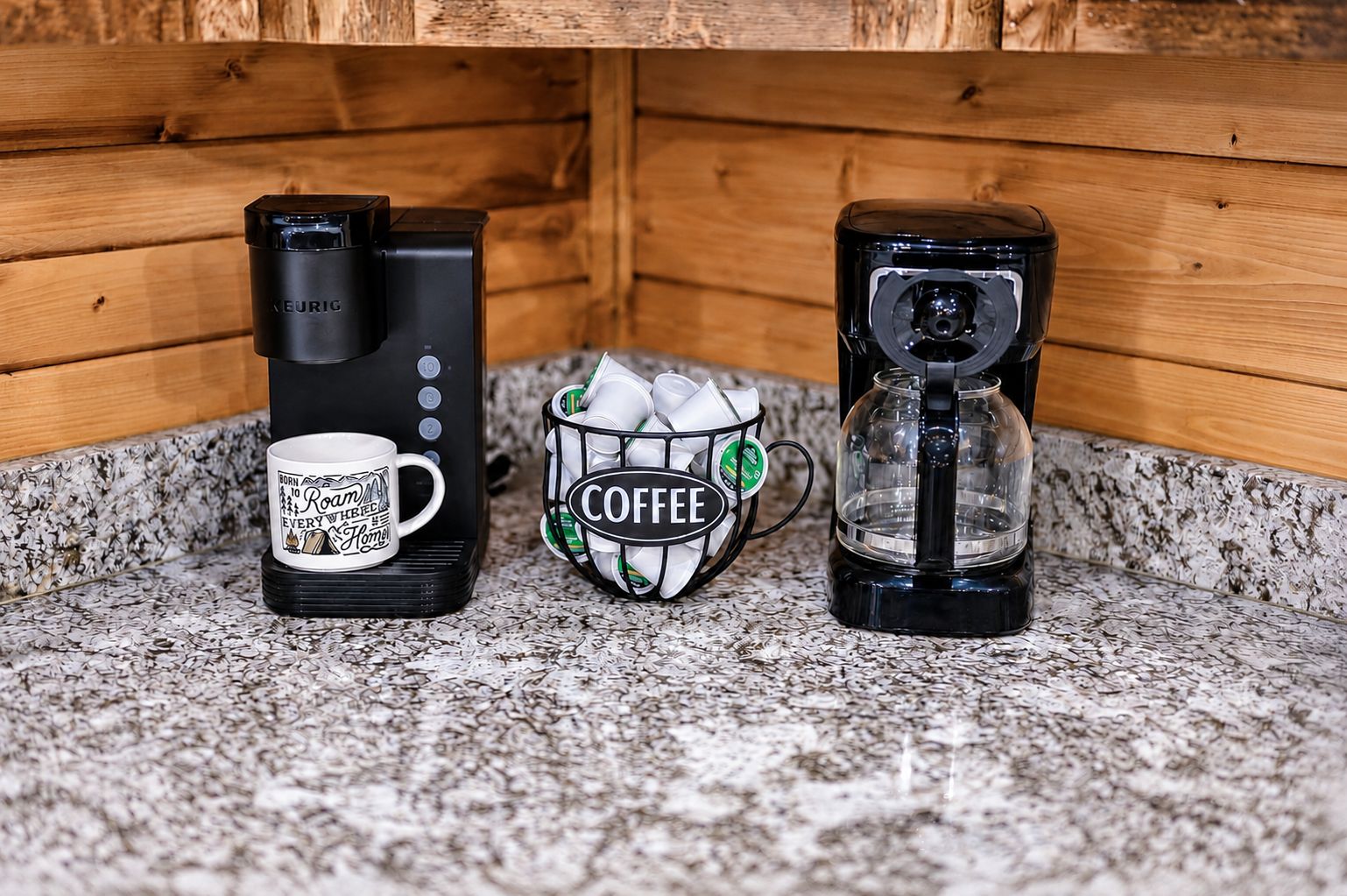 Une machine à café, une tasse et une cafetière sur un plan de travail en granit.