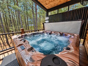 A hot tub with a wooden exterior, surrounded by a wooden deck, with a sign indicating spa rules.