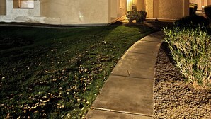 Una casa residencial con techo de tejas rojas, un camino de hormigón que lleva a la entrada y un césped bien cuidado.