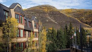 Een meerlaags gebouw met een modern architectonisch ontwerp, gelegen in een bergachtig landschap met herfstkleuren.