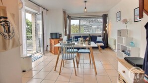 A cozy room with a dining area, a sofa, a TV, and a bookshelf. - Le Duplex du Linkin - PERROS GUIREC (PERROS GUIREC)