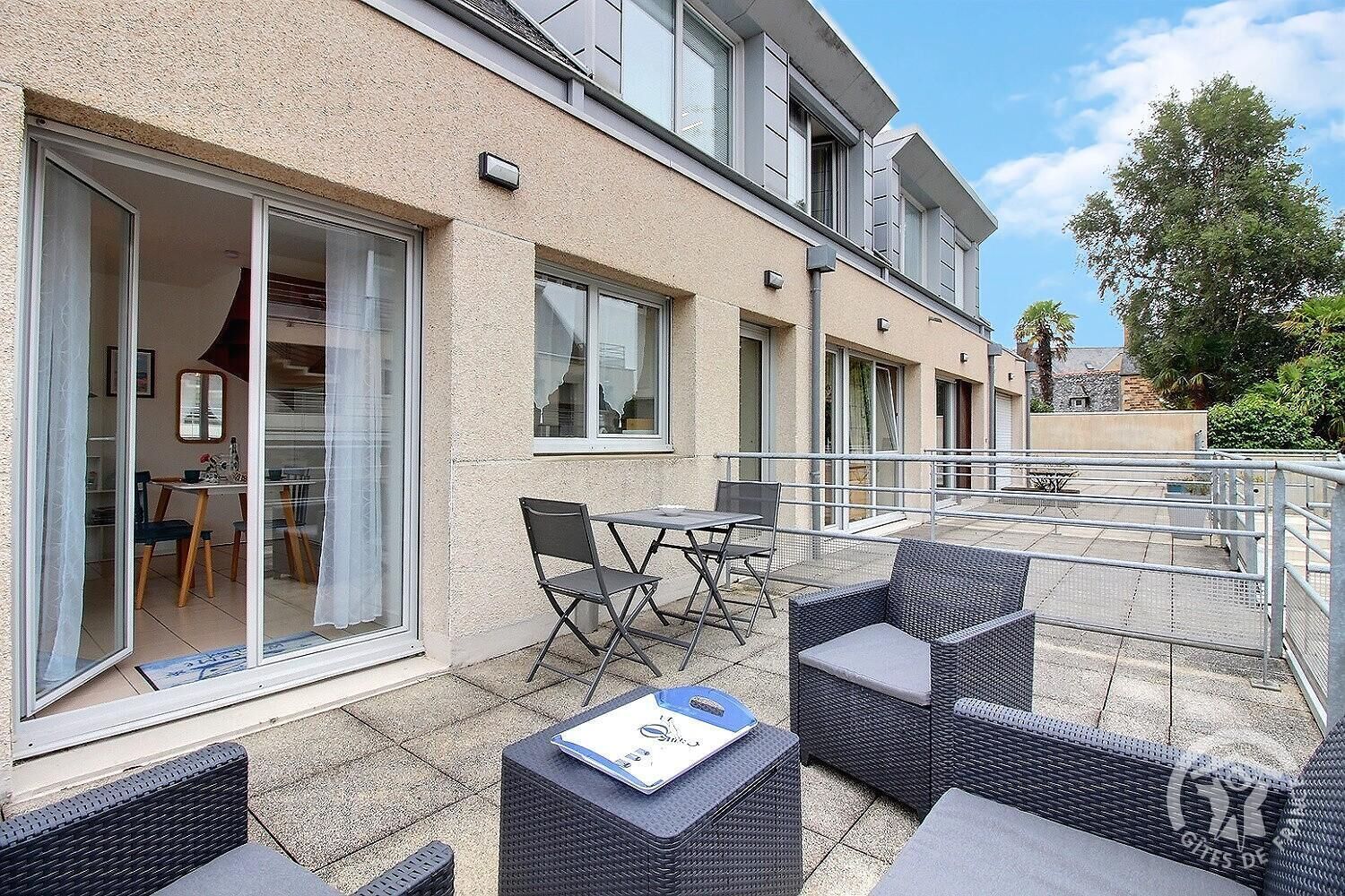 A modern building with a balcony area featuring outdoor furniture and a dining table.