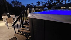 A hot tub with a blue light, wooden stairs, and outdoor furniture. - New Construction with Heated Swim Spa 5,5 mi to the beach with fenced back yard (Port Charlotte)