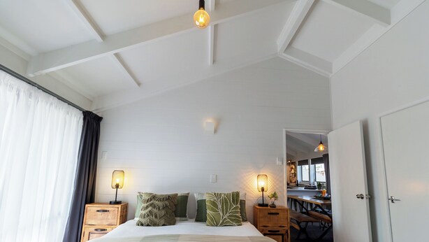 Una habitación de hotel con cama, lámparas de noche, mesita de noche y vista al área de la cocina.