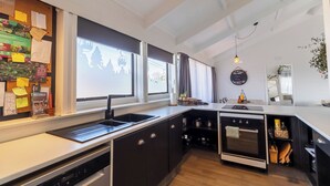 Una cocina moderna con horno empotrado, lavavajillas y un amplio ventanal con vistas a un paisaje urbano.