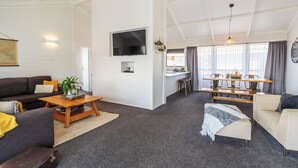 Un salón amplio con sofá, una mesa de centro y un televisor montado en la pared.