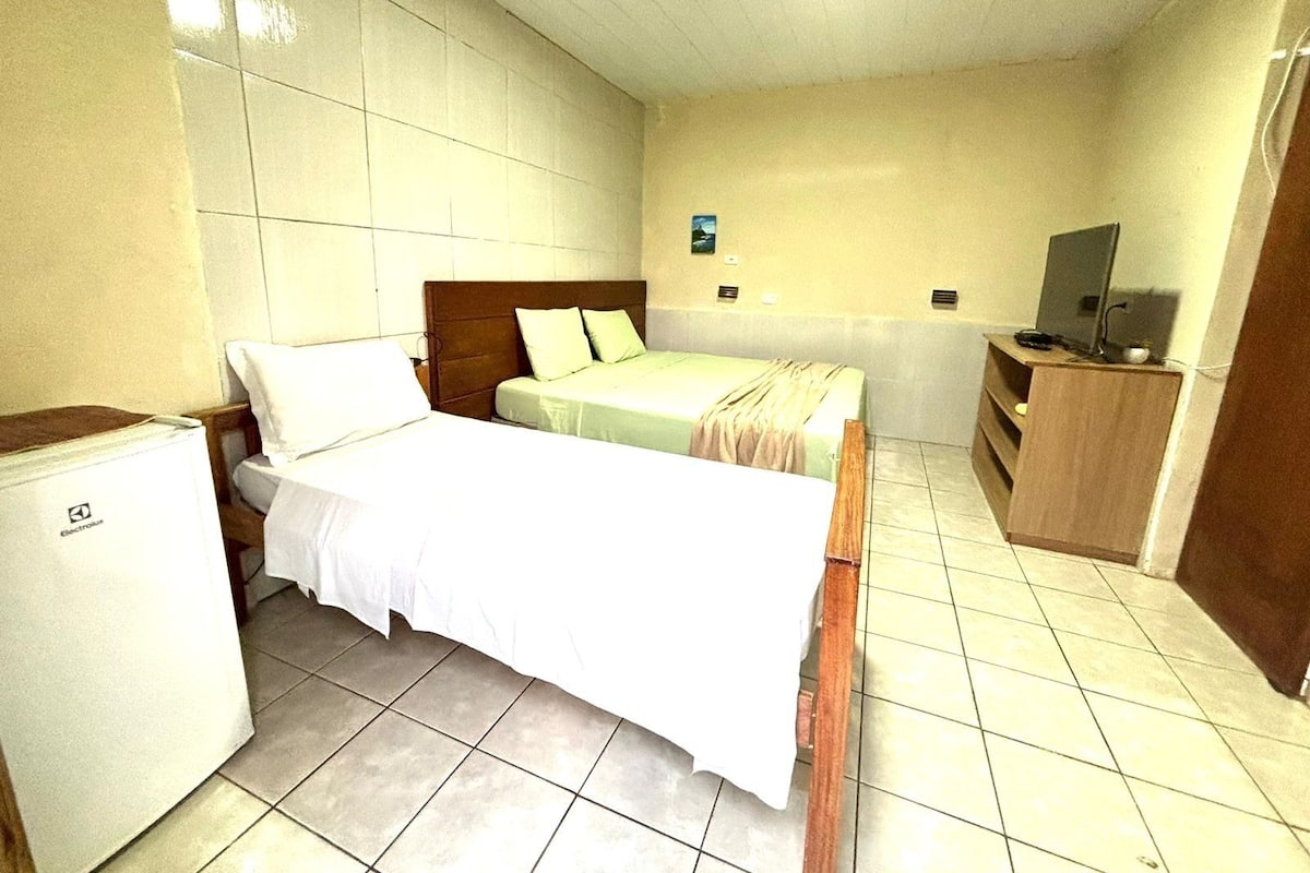 Une chambre d’hôtel équipée d’un lit, d’un petit réfrigérateur, d’une télévision et d’un bureau.