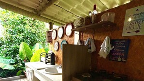 A kitchen area with a sink, stove, and various kitchen items. There are plates hanging on the wall and a sign that says "Comer Hoje". - Pousada Porto de Paz Noronha (Fernando de Noronha)