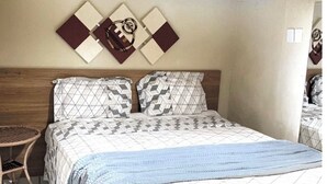 A bedroom with a bed, a small round wicker table, and a wall-mounted artwork. - Pousada Porto de Paz Noronha (Fernando de Noronha)