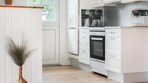 A modern kitchen with white cabinetry, a built-in oven, and a coffee maker. - 3 bedroom beautiful home in Thyholm (Thyholm)