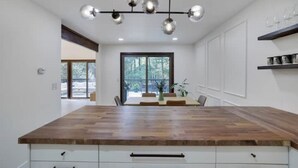 A modern kitchen with a large island, white cabinetry, and a hanging light fixture. - King David Luxury getaway (Blakeslee)