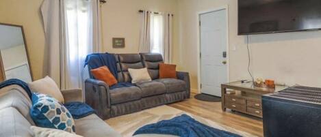 A living room with a sofa, a coffee table, and a flat-screen TV.