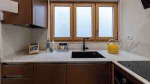 A kitchen with a black sink, a yellow kettle, and a window above the sink. - House Bacco (Firenze)