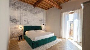 A bedroom with a green upholstered bed, a white rug, a wooden ceiling, and a mural on the wall. - House Bacco (Firenze)