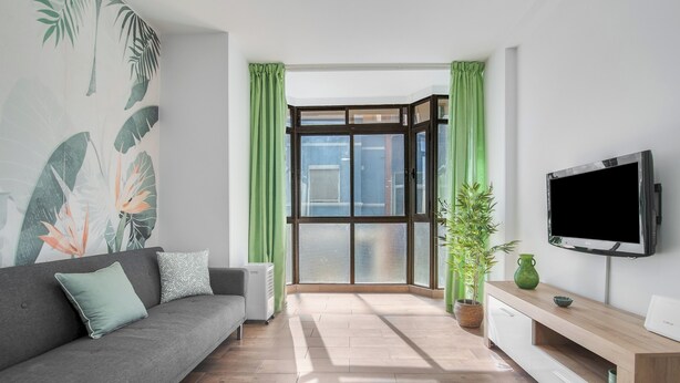 A modern living room with a grey sofa, a flat-screen TV, and a wooden cabinet.