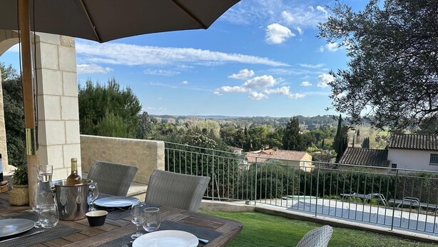 Ein Essbereich im Freien mit Korbmöbeln, einem Metalltisch und Blick auf die Landschaft.