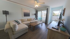 A living room with a sofa, coffee table, and a ceiling fan.