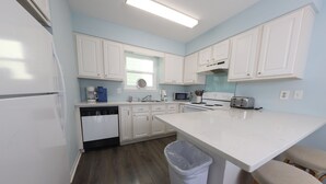 A kitchen with white cabinets, a microwave, a toaster, and a dishwasher.