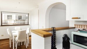 A modern kitchen with white cabinetry, a wooden countertop, and a microwave. - LaDolcevita - Ponte Milvio Stunning View Penthouse (Roma)