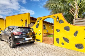 A black Renault Clio parked in front of a yellow building with a distinctive archway and stone-like features.