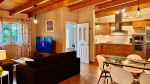 A modern living room with a TV, sofa, and dining area with chairs and a glass table. - House in rural environment, Teide views, zen garden and BBQ (ideal for families). (Santa Bárbara)