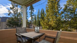 Eine Terrasse im Freien mit Tisch und Stühlen, umgeben von Holzgeländern und Bäumen.
