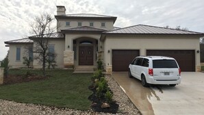 Une maison à deux étages avec un garage, une allée et un petit jardin.