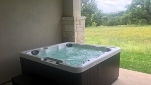 Un bain à remous avec un mur en pierre et une pelouse verdoyante en arrière-plan.