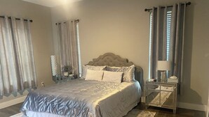 Une chambre à coucher avec un grand lit, des tables de chevet, une commode et une lampe.